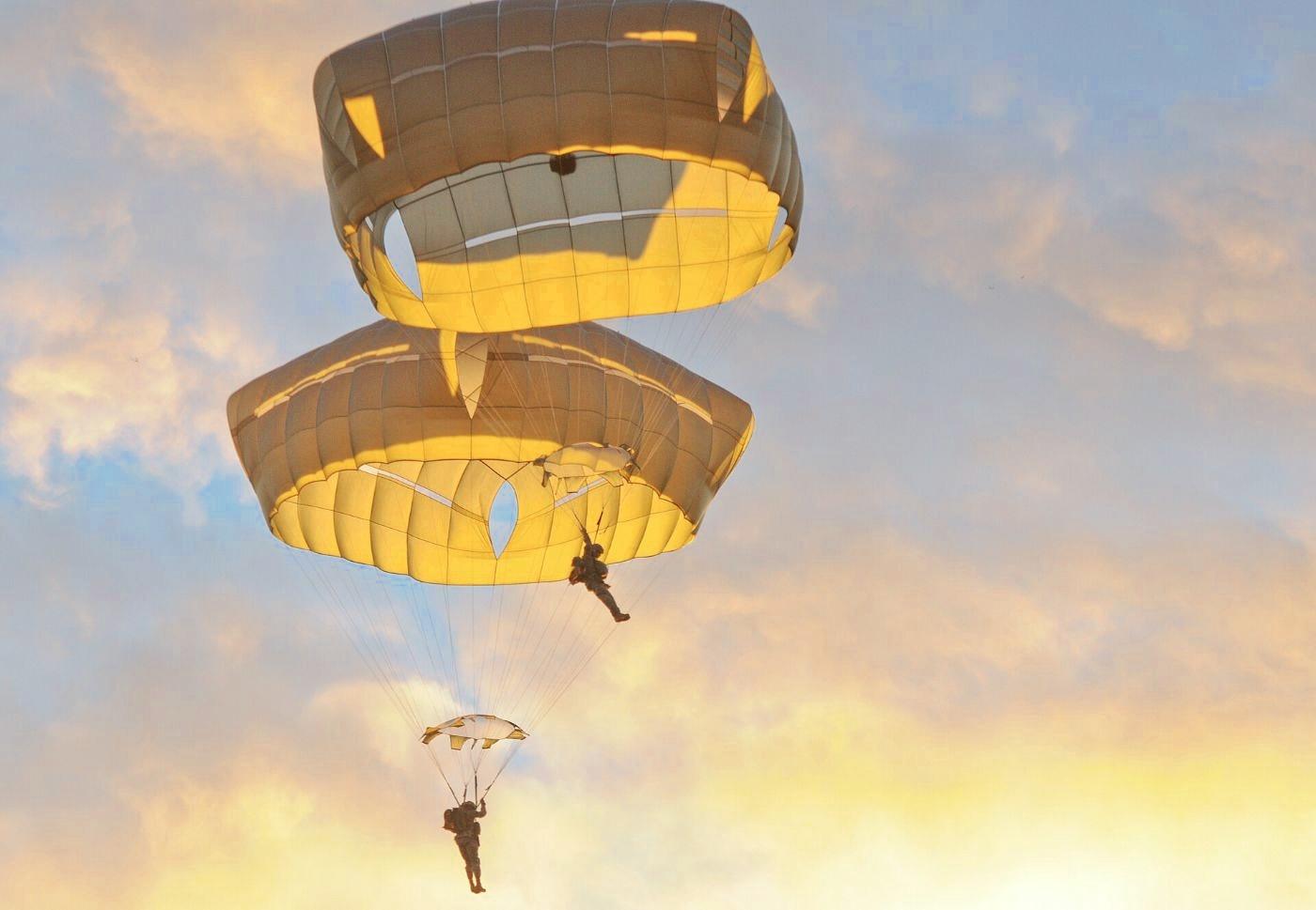 Paratroopers descending under T-11 parachutes at sunset